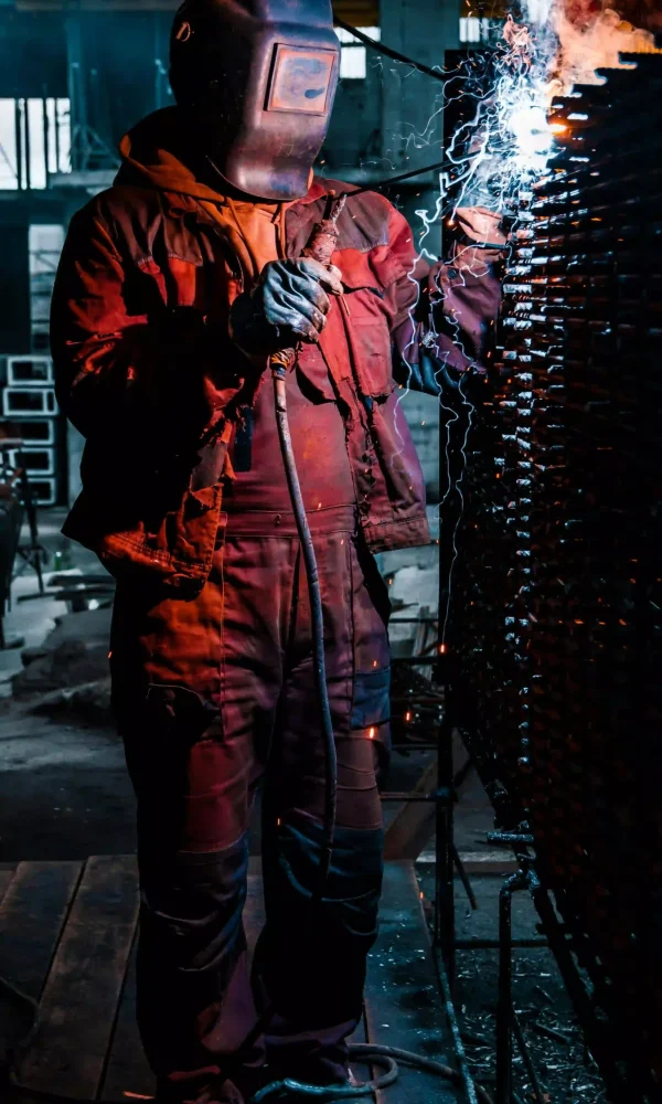 Industrial welding repair work on heavy equipment in a workshop.